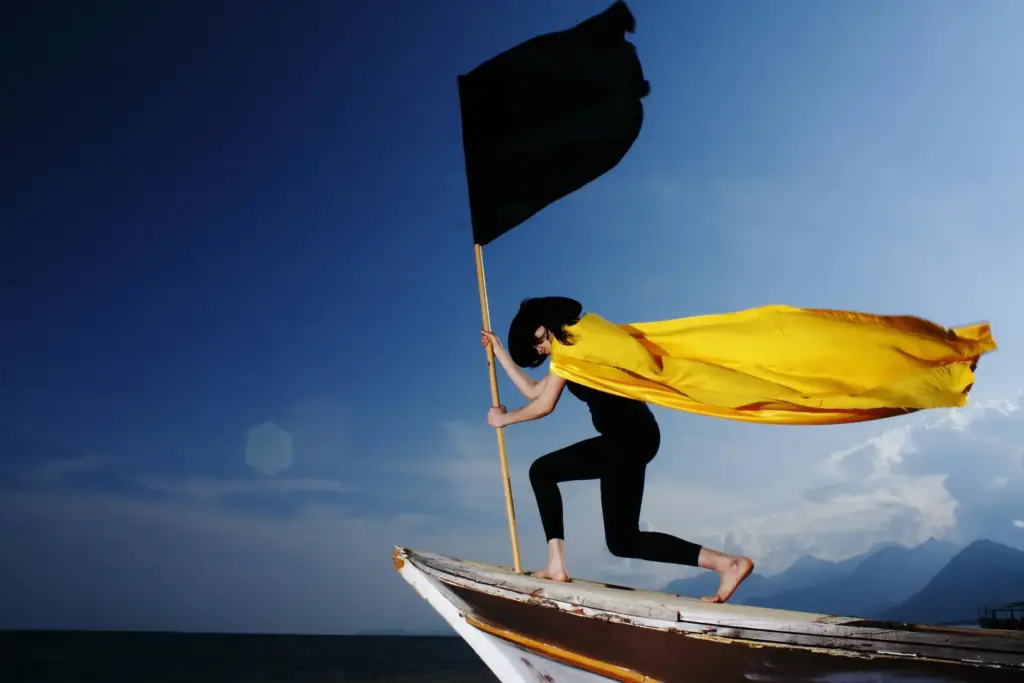Frau mit schwarzer Flagge an der Spitze eines Boots auf ihrer Heldenreise