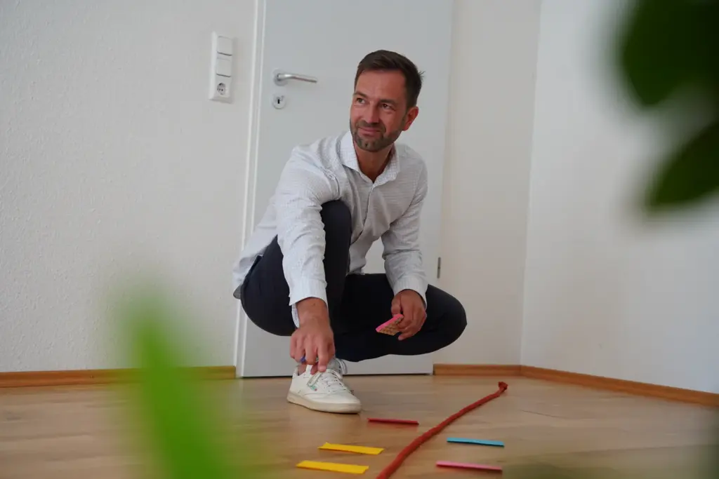 startseite-coaching-prozess-thomas-waaden Thomas Waaden ordnet Karten und ein Seil für eine Coachingübung auf dem Boden.